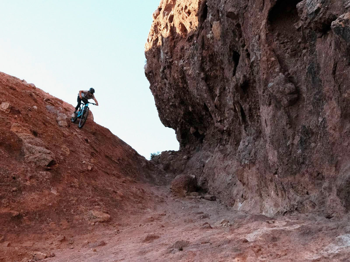 Rider dropping into a red rock chute beside a tall cliff on a 2027 Santa Cruz Nomad in Arizona