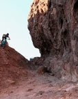 Rider dropping into a red rock chute beside a tall cliff on a 2027 Santa Cruz Nomad in Arizona