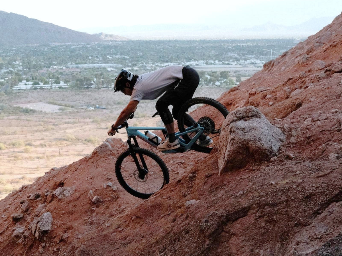 Rider on a very steep red rock descent on a 2027 Santa Cruz Nomad with desert valley views in Arizona