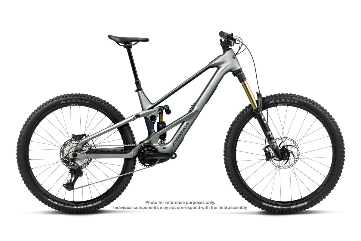 A full-suspension mountain bike with a metallic gray frame, black knobby tires, a black saddle, and gold front fork accents, shown against a plain white background.