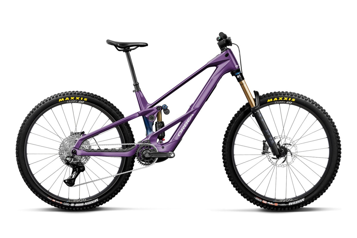 A purple full-suspension mountain bike with black Maxxis tires and a gold Fox fork, shown from a side profile on a white background.